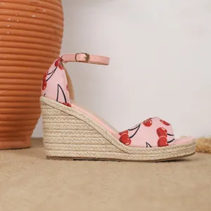 Nahaufnahme einer rosa Keilsandalette mit Kirschprint und gewebtem Plateau-Detail