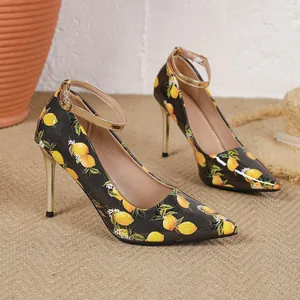 Detail of women's lemon print high heels with golden ankle straps and stiletto heels.