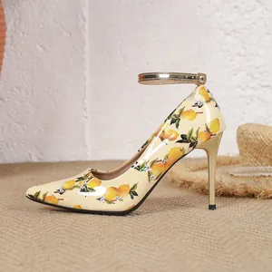 Detail view of high-heeled shoe featuring summery lemon print and golden stiletto heel