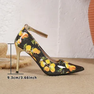 Detailed view of the 9.3cm gold stiletto heel on a fruit print pointed toe pump
