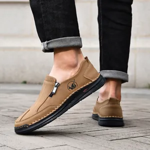 Close-up of men's casual brown leather loafers with detailed hand-stitching on pavement