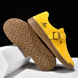 Vista detallada de zuecos amarillos estilo Birkenstock con hebilla de metal y suela blanda.
