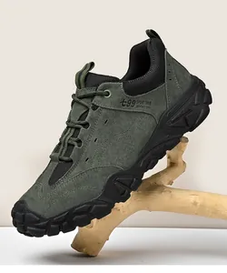 Vue latérale détaillée d'une chaussure de randonnée en daim vert foncé sur une branche