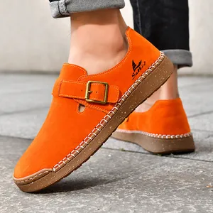 Primer plano de mocasines planos de ante naranja con hebilla y suela de goma suave y cómoda