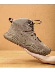 Detailed side view of a brown suede winter hiking boot with rugged sole held by hand