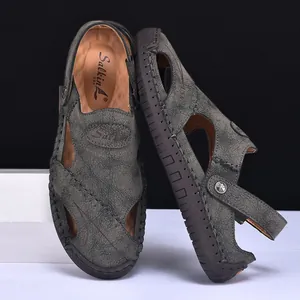 Detail showing men's dark grey leather sandals with intricate hand-stitched craft.