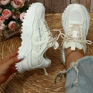 Witte chunky platform sneakers met ademend mesh en dikke zolen op een strooien mat