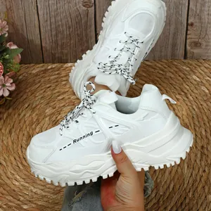 Detailopname van witte plateau-sneakers met Running-tekst op een geweven strooien matje.