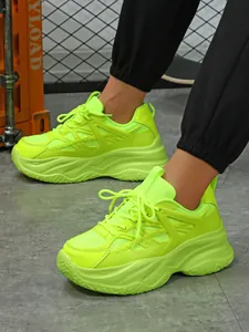 Gros plan de baskets compensées vert néon stylées pour femmes portées au pied
