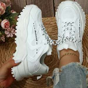 Detailweergave van witte chunky platform sneakers met ademend mesh op geweven mat.