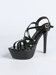 Close-up view of black patent leather high heel sandals with platform and cross straps