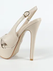 Detalle de sandalia de tacón de aguja beige con plataforma y dije de cristal