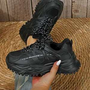 Zijaanzicht van zwarte trendy platform sneakers vastgehouden boven een strooien mat