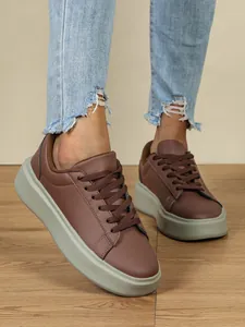 Detailansicht brauner Plateau-Sneaker mit dicken Sohlen und zerrissenen Jeans