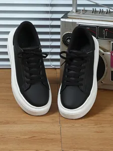 Vooraanzicht van zwarte dames sneakers met plateauzool, dikke witte zolen en veters.