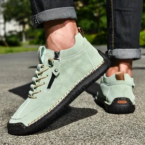 Close-up of men's light green suede casual boots with side zipper and black rubber sole.