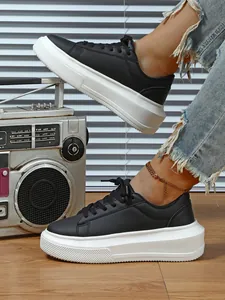 Detail van zwarte damesplateausneakers met dikke witte zolen aan de voeten van een model