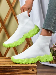 Detail van witte gebreide sok-sneakers met levendige neongroene dikke platformzolen