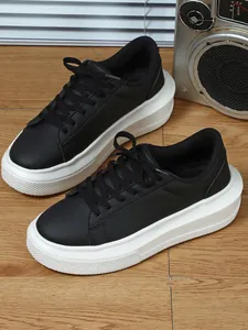 Zijaanzicht van zwarte dames sneakers met plateauzool en dikke witte zolen op hout