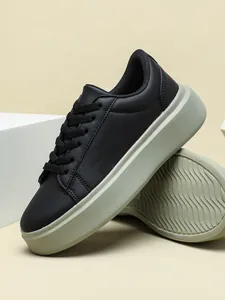 Detailansicht stilvoller schwarzer Damen-Plateau-Sneaker mit einzigartiger grüner Wellensohle