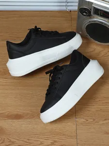 Detailweergave van stijlvolle zwarte platform sneakers met dikke witte rubberen zolen