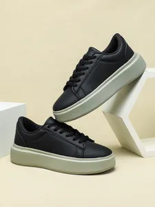 Detailansicht schwarzer Plateau-Sneaker mit grauer klobiger Sohle, Schnürsenkeln und Design.
