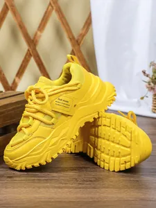 Detail van gele chunky platform sneakers met zijlabel en getextureerde buitenzool