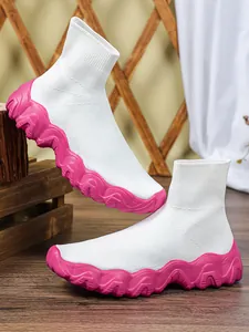 Detail van ademende witte gebreide sneakers met dikke roze golvende zolen voor dames.