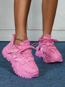 Vista macro dettagliata di sneakers rosa chunky con suole spesse e stringhe.