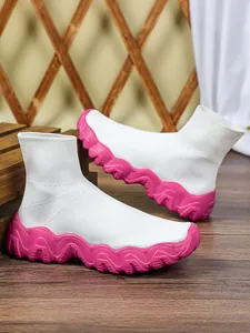 Detailopname van witte gebreide sok-schoenen met levendige roze golvende dikke zool