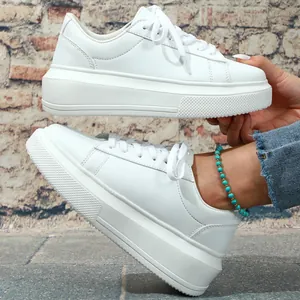 Detailopname van witte plateau sneakers voor dames met dikke zolen en vetersluiting.