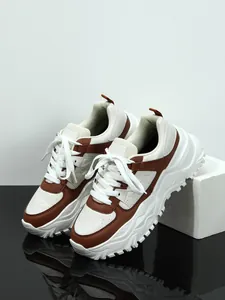 Detail of chunky sneakers with white and brown panels and a thick serrated sole.