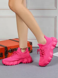 Leuchtend pinke Fly-Knit-Sneaker am Modell, Detailansicht mit vintage orangefarbenem Koffer.
