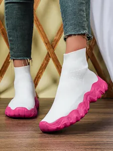Witte gebreide sok-schoenen met een opvallende roze gegolfde zool en ademend gaas.