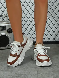 Detailed view of chunky platform sneakers in brown and white contrast colors