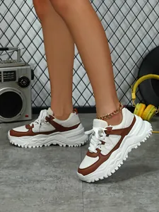 Detailed macro view of comfortable brown and white chunky sneakers with thick soles.