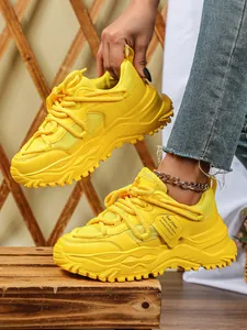 Close-up van felgele chunky sneakers met ademend mesh en een dikke platformzool