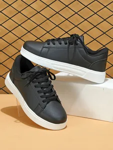 Dettaglio di sneaker in ecopelle nera con suola bianca spessa su un blocco bianco