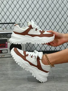 Close-up detail of brown and white chunky sneakers featuring a thick white platform sole