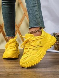 Gedetailleerde close-up van felgele chunky dad-sneakers met een dikke platformzool.