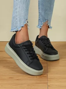 Detailansicht schwarzer Plateau-Sneaker mit dicker grauer Sohle, getragen zu Jeans