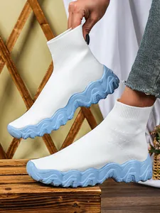 Detail van witte gebreide sok-sneakers met een lichtblauwe golvende platformzool