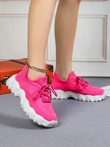 Detailansicht pinkfarbener Fly-Knit-Plateau-Sneaker mit goldener Fußkettchen-Kette.