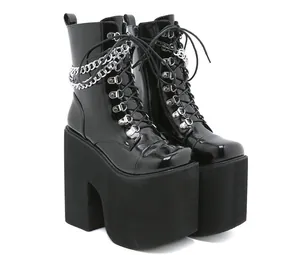 Close-up of black patent leather platform boots with chunky heels and silver chains