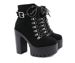 Detailed view of black suede platform boots featuring high block heels and silver buckle straps