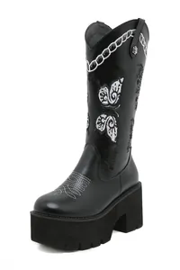 Close-up of retro black platform tall boot featuring intricate white butterfly embroidery