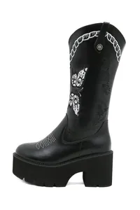 Detail of retro black Western boots with white butterfly embroidery and platform sole.