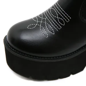 Detailed close-up of white decorative embroidery on black leather platform western boots