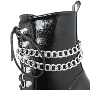Close-up detail of black patent leather platform boots with silver chain and lace-up