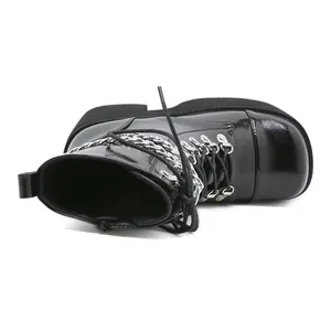 Close-up side view of shiny black patent leather platform boots with metal chain detail.